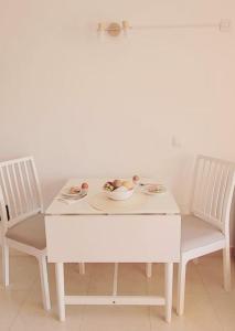 d'une table blanche et de deux chaises avec des assiettes. dans l'établissement Studio Añoreta Playa y Golf, à Torre de Benagalbón