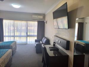 a hotel room with a bedroom with a desk and a tv at Australian Homestead Motor Lodge in Wagga Wagga