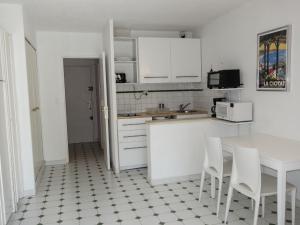 cocina con armarios blancos, mesa y sillas en Apartment Jardins de la mer-10 by Interhome, en Saint-Cyr-sur-Mer