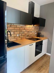 uma cozinha com armários brancos e uma parede de tijolos em Chillout Loft Apartment AL20 em Varósvia