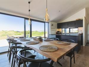 uma cozinha e sala de jantar com uma mesa de madeira e cadeiras em Holiday Home Kristiina - 500m from the sea in NW Jutland by Interhome em Saltum