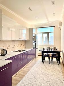 a kitchen with purple cabinets and a table with chairs at Жилой комплекс Green Park in Aktau