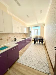 a large kitchen with purple cabinets and a table at Жилой комплекс Green Park in Aktau