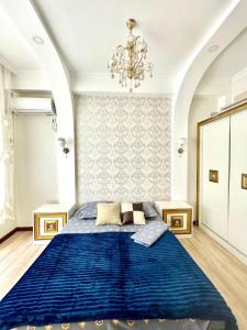 a bedroom with a blue bed and a chandelier at Жилой комплекс Green Park in Aktau