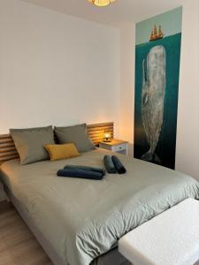 a bed in a room with a painting on the wall at Charme des quais, proche centre et plage in Dunkerque