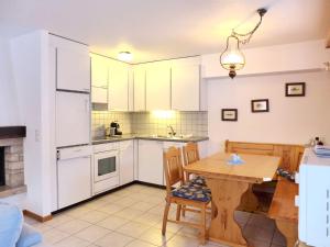 uma cozinha com armários brancos e uma mesa de madeira em Apartment Chalet Papillon by Interhome em Bürchen