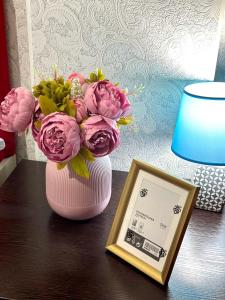 阿克套的住宿－ЖК Тыныштык，粉红色的花瓶,桌子上放着一束鲜花