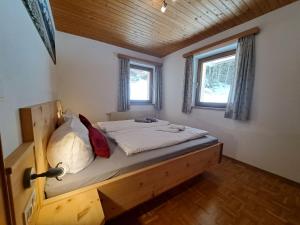 een slaapkamer met een bed in een kamer met twee ramen bij Apartment Waldruhe by Interhome in Auffach