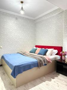 a bedroom with a bed with blue and white pillows at ЖК Тыныштык in Aktau