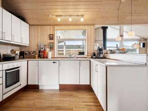 cocina con armarios blancos y techo de madera en Holiday Home Aron - 225m from the sea in SE Jutland by Interhome, en Børkop
