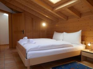 een slaapkamer met een wit bed en een houten plafond bij Apartment Chalet Pfingstrose by Interhome in Grindelwald