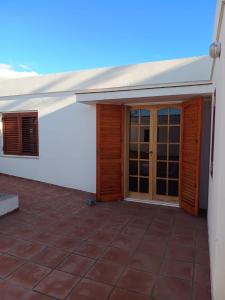 un patio exterior de una casa con puertas de madera en Casiopea Apart en San Fernando del Valle de Catamarca