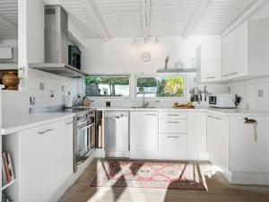 una cucina bianca con armadi bianchi e un tappeto di Holiday Home Sylvia - 450m from the sea in Djursland and Mols by Interhome a Rønde