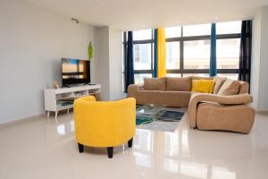 ein Wohnzimmer mit einem Sofa, einem Tisch und gelben Stühlen in der Unterkunft Apartamento Santo Antonio I - T3 in Praia
