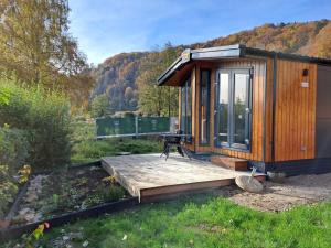 a wooden cabin with a table on a wooden deck at Holiday Home Tiny Haus Prinz Ludwig by Interhome in Riedenburg