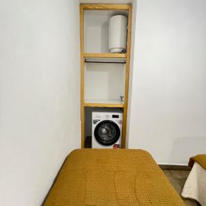 a small room with a bed and a microwave at Bajo Izquierda el Wiro in Puerto
