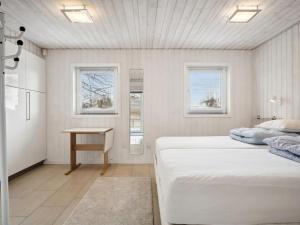 een witte slaapkamer met 2 bedden en een tafel bij Holiday Home Beske - 130m from the sea in SE Jutland by Interhome in Odder