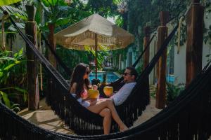 a man and woman sitting in a hammock with a baby at Olbil Hotel Boutique in Valladolid