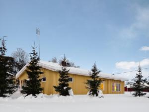 a yellow building with trees in the snow at Holiday Home Saajola by Interhome in Leppäjärvi