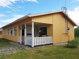 a small yellow house with a white porch at Holiday Home Saajola by Interhome in Leppäjärvi