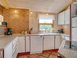 a kitchen with white cabinets and a brick wall at Holiday Home Svenger - 800m from the sea in NW Jutland by Interhome in Fjerritslev