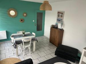 a living room with a table and chairs in a room at Appartement terrasse privée grande plage à 100 m - Parking gratuit in Saint-Cast-le-Guildo