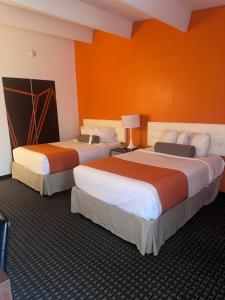 two beds in a hotel room with orange walls at Howard Johnson by Wyndham Newburgh in Newburgh