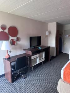 a hotel room with a desk with a television and a bed at Howard Johnson by Wyndham Newburgh in Newburgh