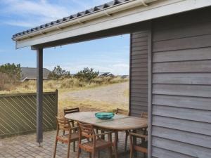 TorstedにあるHoliday Home Ani - 600m from the sea in NW Jutland by Interhomeの木製テーブルと椅子(日よけ付)が備わるパティオ