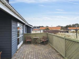 eine Terrasse mit 2 Stühlen und einem Tisch auf einem Zaun in der Unterkunft Holiday Home Ani - 600m from the sea in NW Jutland by Interhome in Torsted