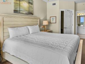 een slaapkamer met een groot bed met een witte sprei bij SMP 504 - 3 BR Beachfront Condo - Sleeps 10! in Fort Walton Beach