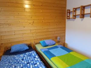 two beds in a room with wooden walls at Tatry TOP Dom in Vavrišovo