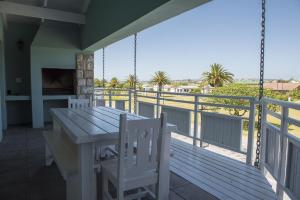 a porch with a wooden table and chairs on a balcony at Osler Place Self-Catering in Stilbaai