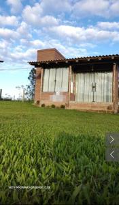 a building with a cross in front of a field of grass at Sítio Aconchego dos Canyons in Praia Grande