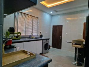 a kitchen with a sink and a washing machine at Plushly-Furnished Three-Bedroom Apartment in Wuye in Abuja