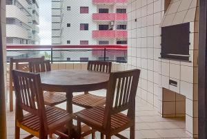 einen Holztisch und Stühle in einem Zimmer mit Fenster in der Unterkunft Apto 3 quartos, churrasqueira, vista para o mar e piscina in Praia Grande