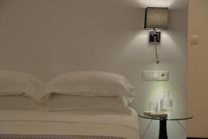 Una cama con sábanas blancas y una mesa con lámpara. en Alter Athens en Athens