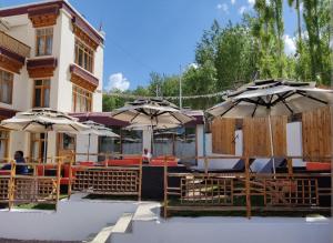 a patio with tables and umbrellas in front of a building at Gomang Boutique Hotel in Leh