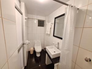a white bathroom with a toilet and a sink at Mapi Gardens Machupicchu B&B in Machu Picchu