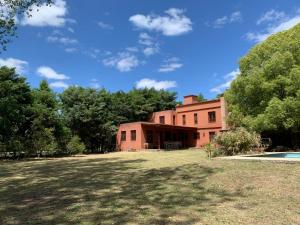 un antiguo edificio de ladrillo rojo con árboles en el fondo en Casa con piscina y gran parque en Los Cardales en Los Cardales