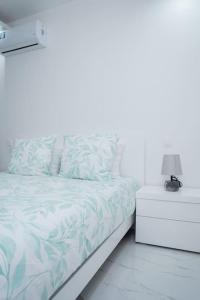 a white bedroom with a bed and a night stand at Saw Paradise in Praia T2 in Praia