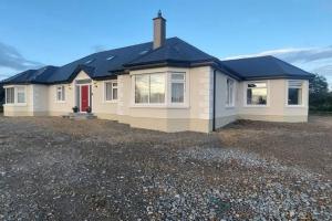 una casa con una puerta roja en un lote de grava en Modern Countryside apartment Killmallock Lodge en Enniscorthy