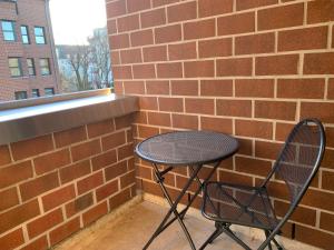 a small table and chair sitting next to a brick wall at Comfort Apartment Düsseldorf Messe 2 rooms with kitchen, balcony, parking and elevator in Düsseldorf