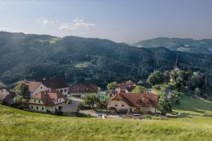a village on a hill with mountains in the background at Gostilna Pension Blegoš in Poljane nad Škofjo Loko
