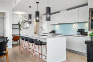 a kitchen with white cabinets and a bar with stools at Manhattan in Calgary