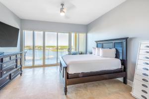 a bedroom with a bed and a television and a balcony at Sailmakers Place 703 in Perdido Key