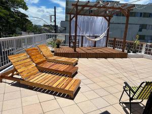 a patio with two wooden benches and a gazebo at Quarto Econômico com Ar Cond. e Smart Tv Netflix in Itajaí