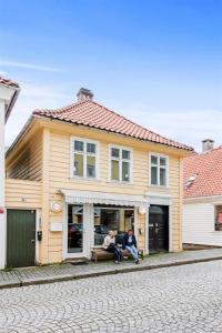 two people sitting on a bench in front of a house at Pepes Apartment in Bergen