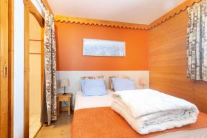 1 dormitorio con paredes de color naranja y 1 cama con sábanas blancas en Résidence Les Hauts Bois - maeva Home - Appartement 3 Pièces 8 Personnes - 034, en Aime La Plagne