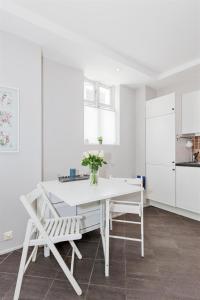 a white kitchen with a white table and chairs at Pepes Apartment in Bergen